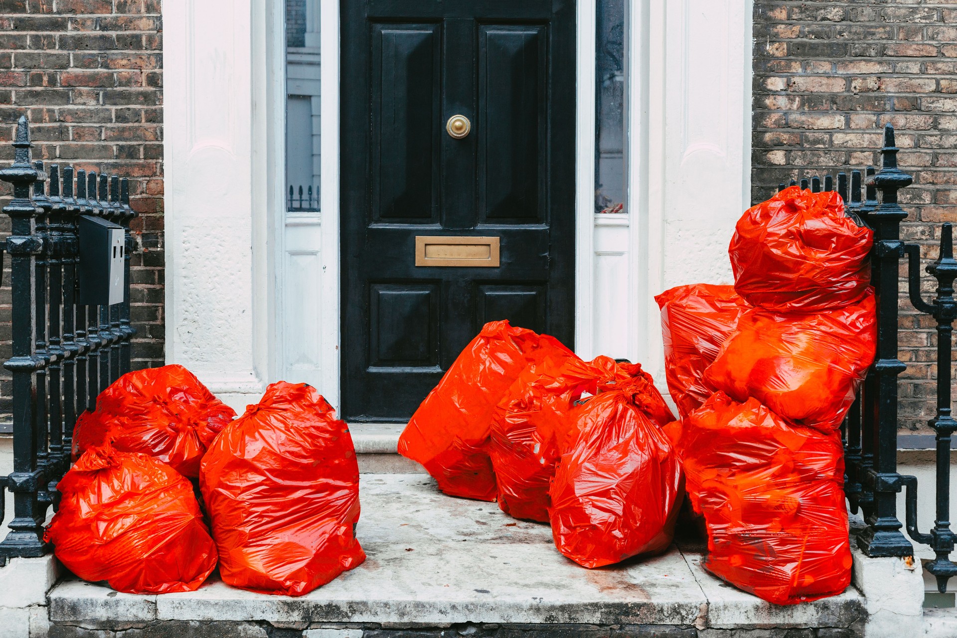 Red garbage bags of household waste on front step outside house